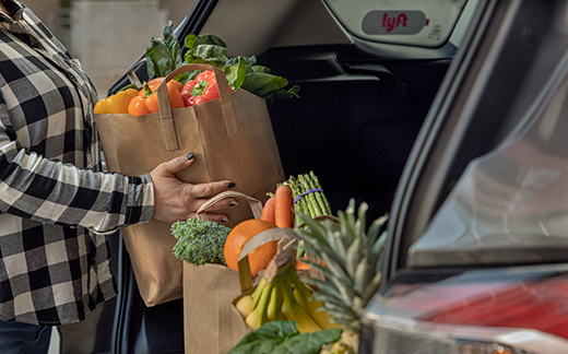 A woman loading grocery bags into the trunk of a Lyft.